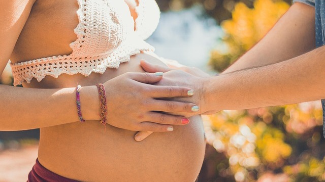 Pregnant woman wearing a maternity bra in a bright room.