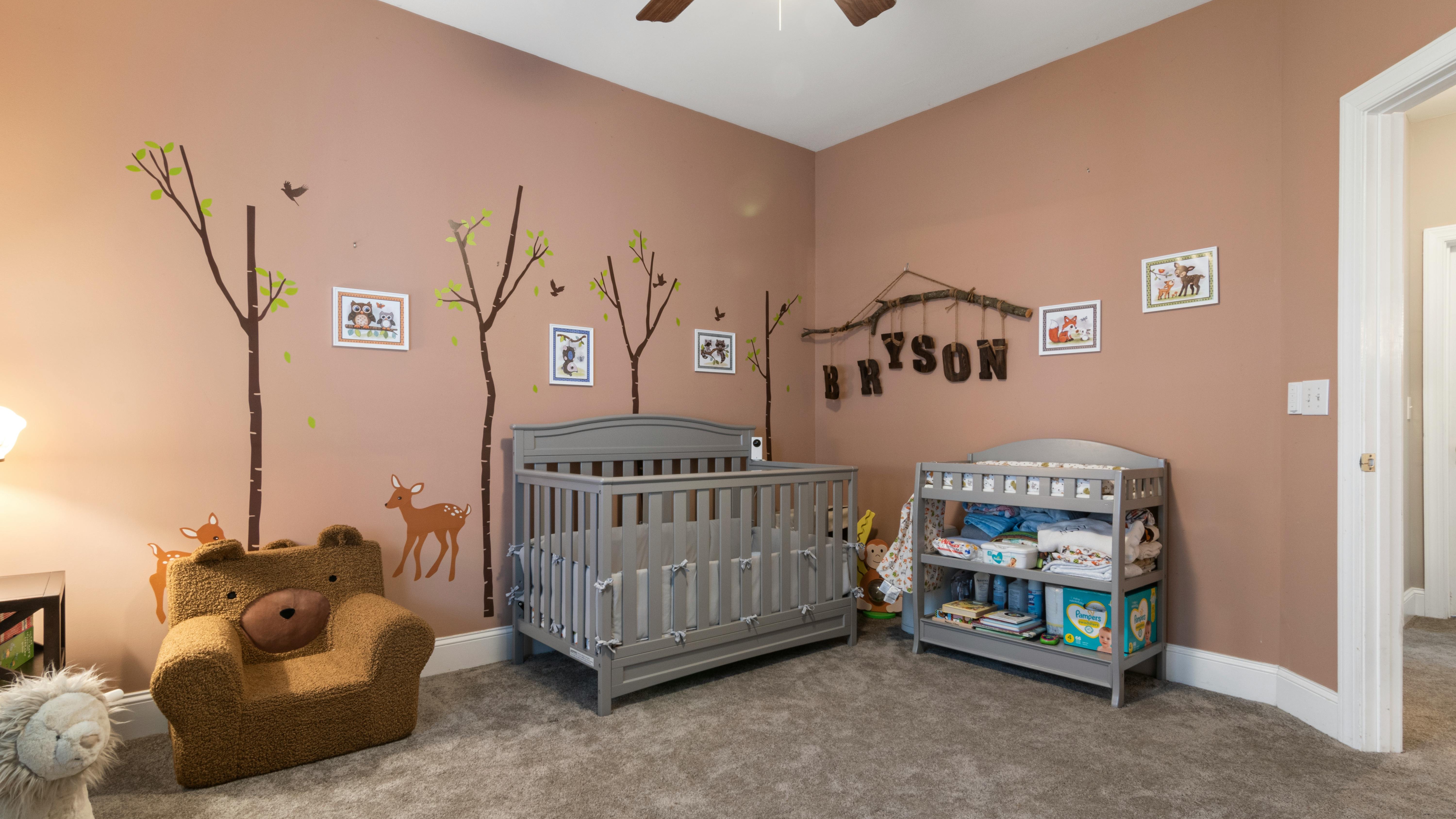 Pregnant woman in nursery with baby registry essentials.