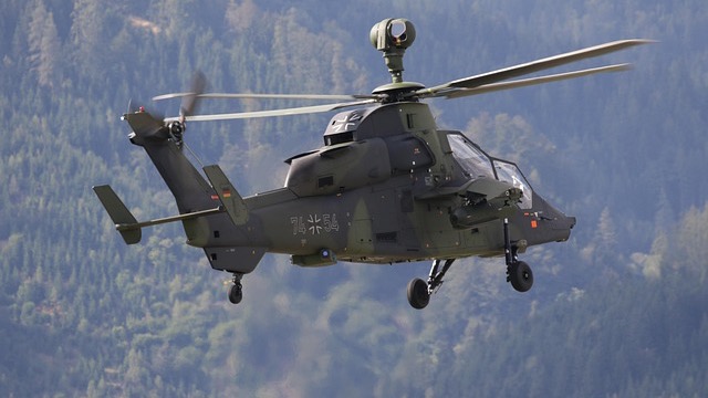 Military helicopter flying over desert related to military contract modifications.