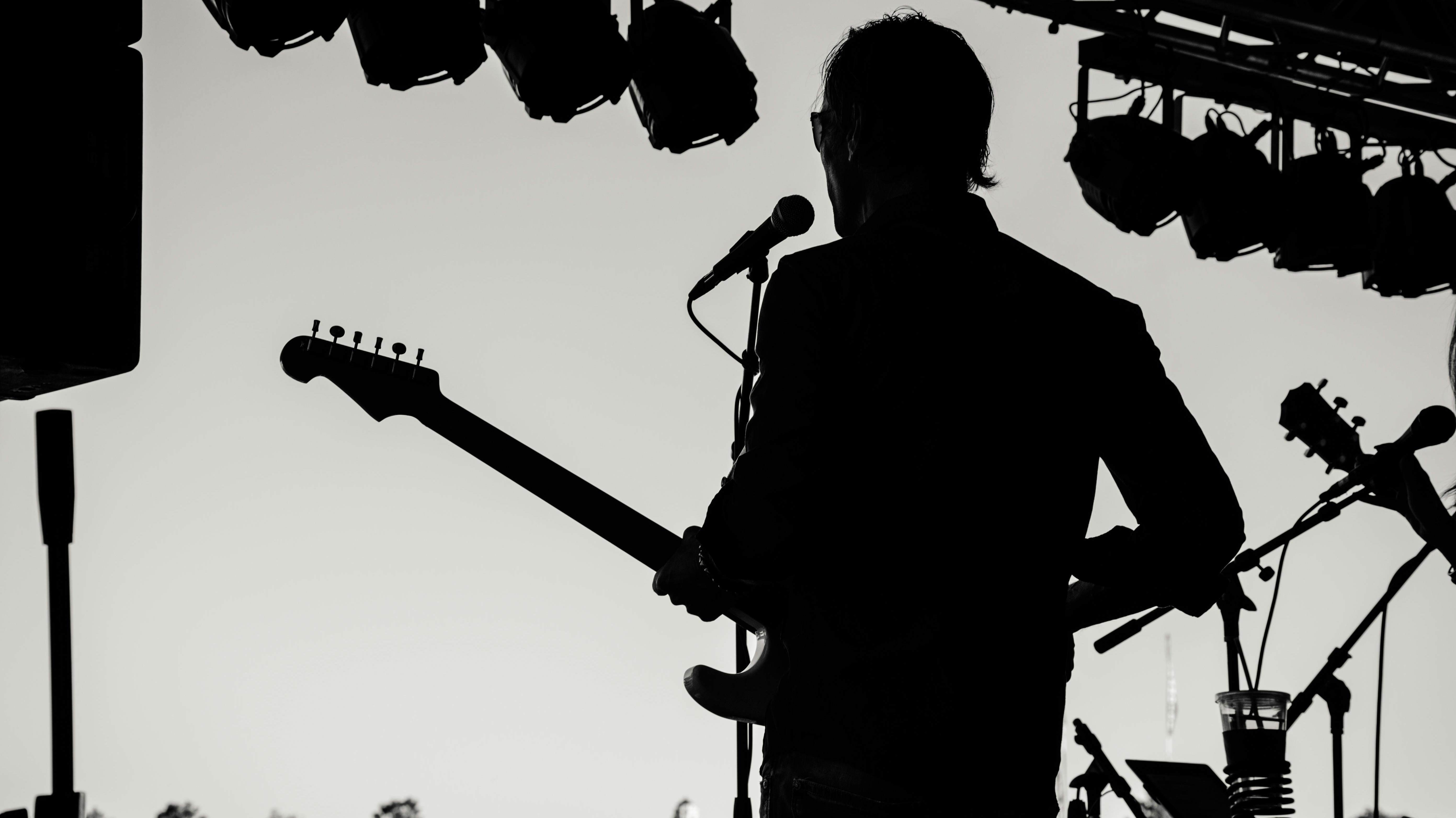 Elderly male musician playing guitar on vibrant stage, live music in Omaha.