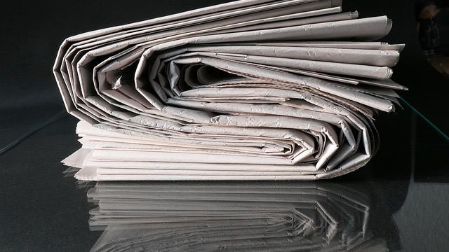 Middle-aged man smiling warmly indoors with family photos on the wall.