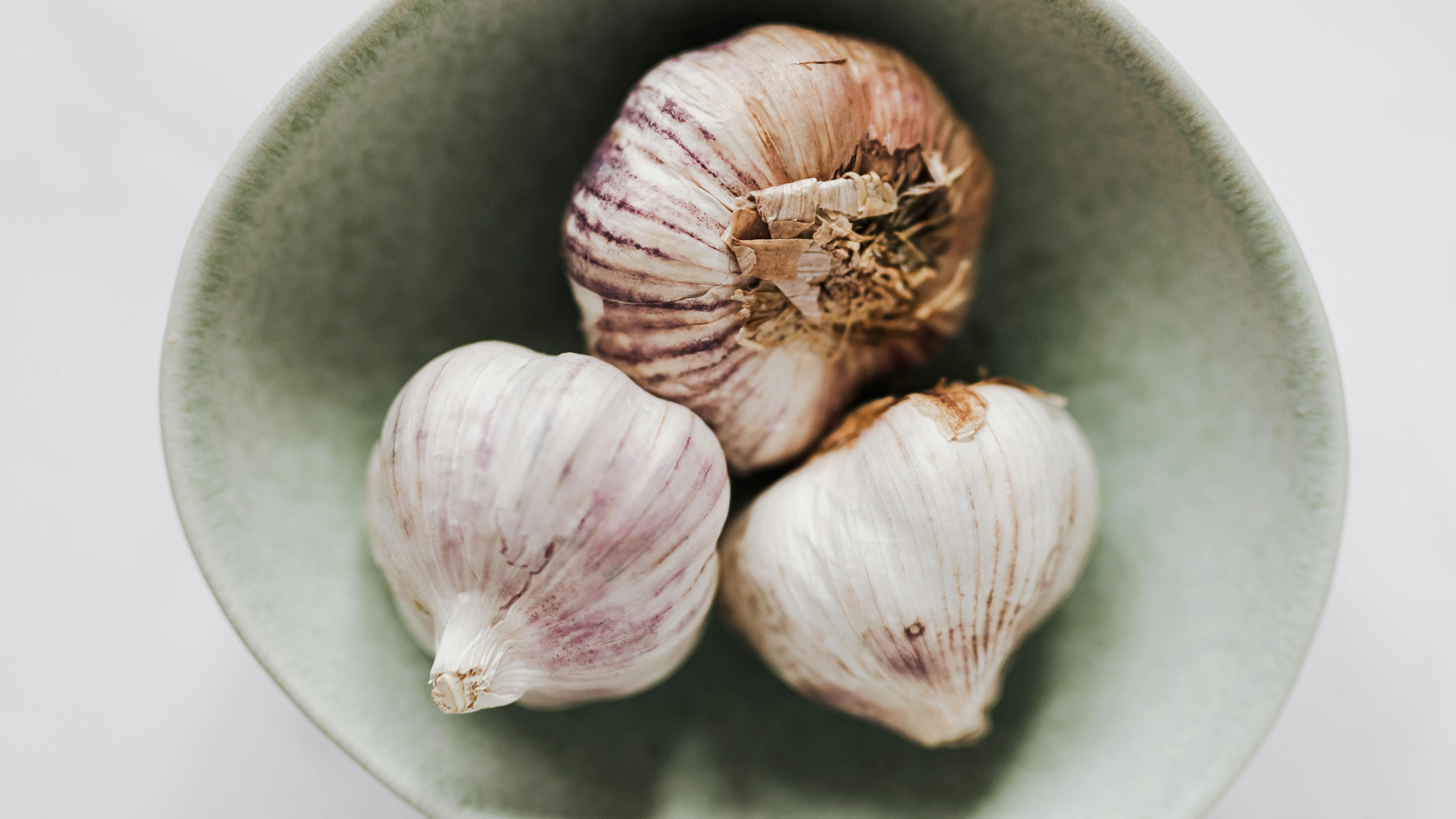 Garlic cloves being planted in soil with a shovel.