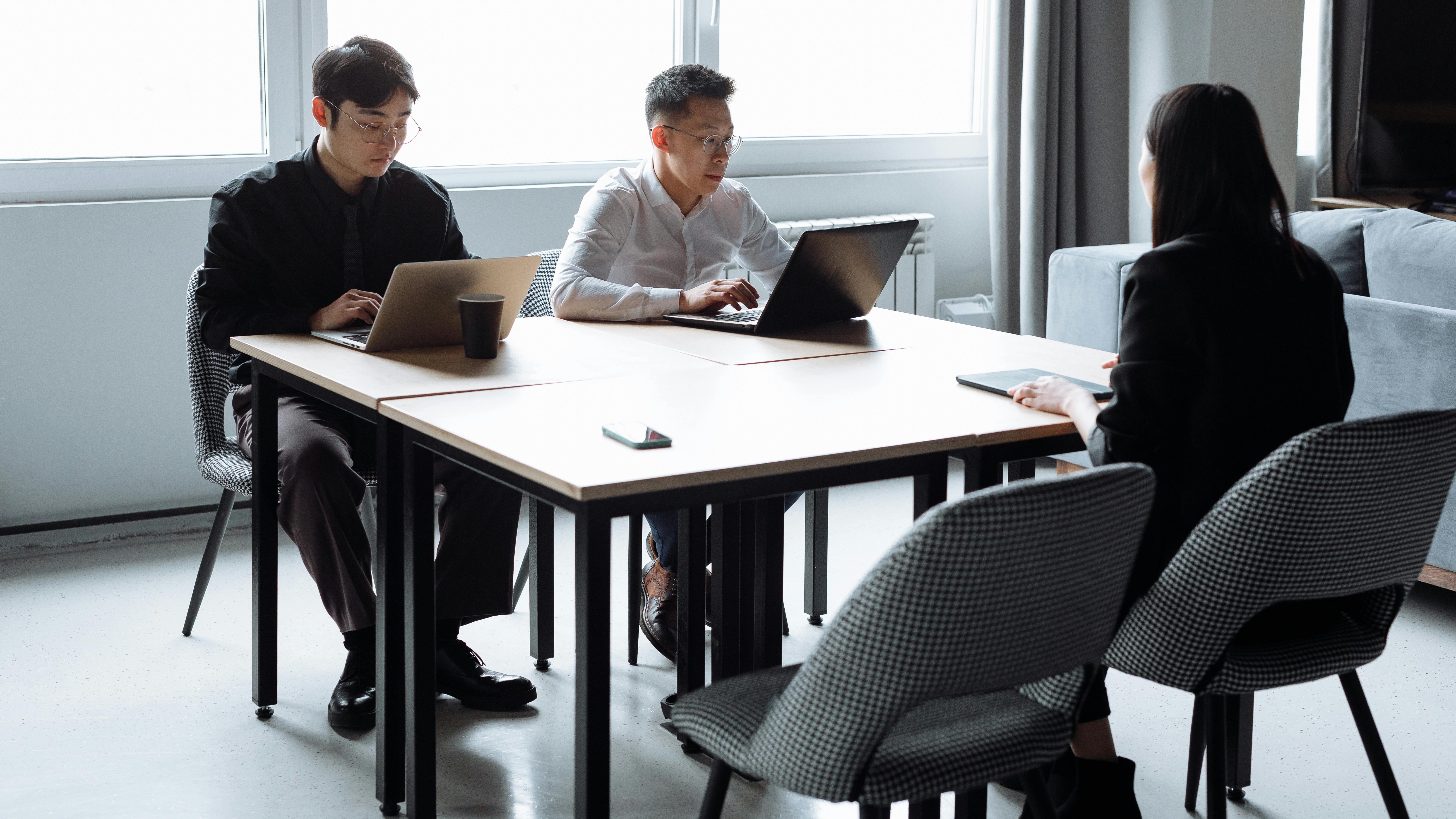 Three women in a modern office discussing documents.