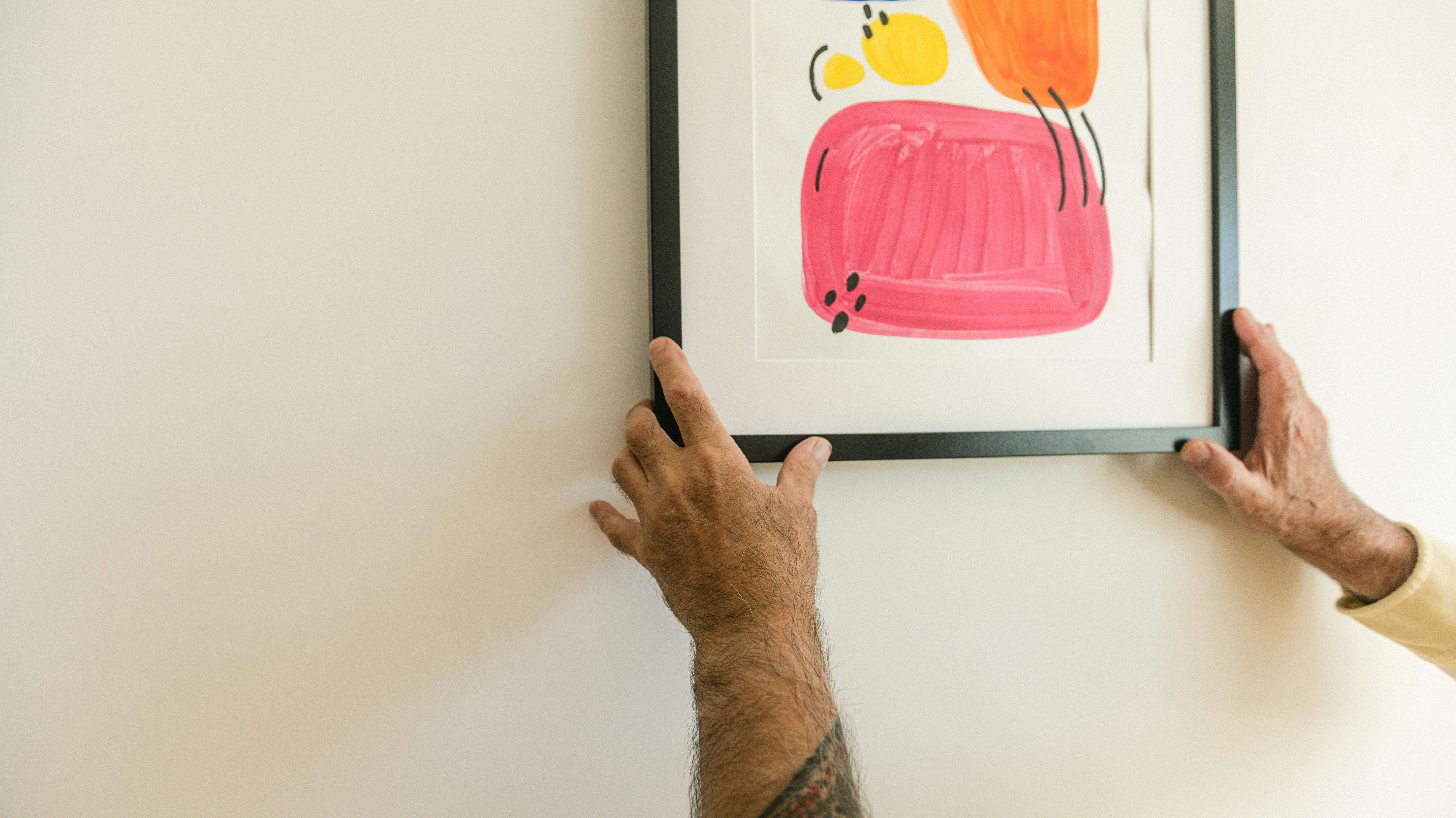 Easy and Inexpensive DIY Picture Frames being placed on a wall.