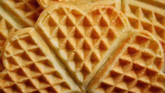 Delicious chocolate chip waffles with syrup and strawberries on a marble table.