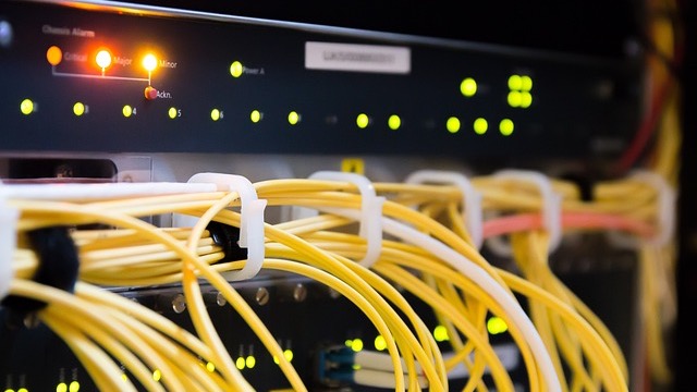 Businessmen discussing broadband infrastructure funding in a modern office.