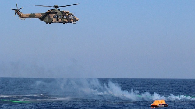 Coast Guard helicopter rescue amid tall pines.