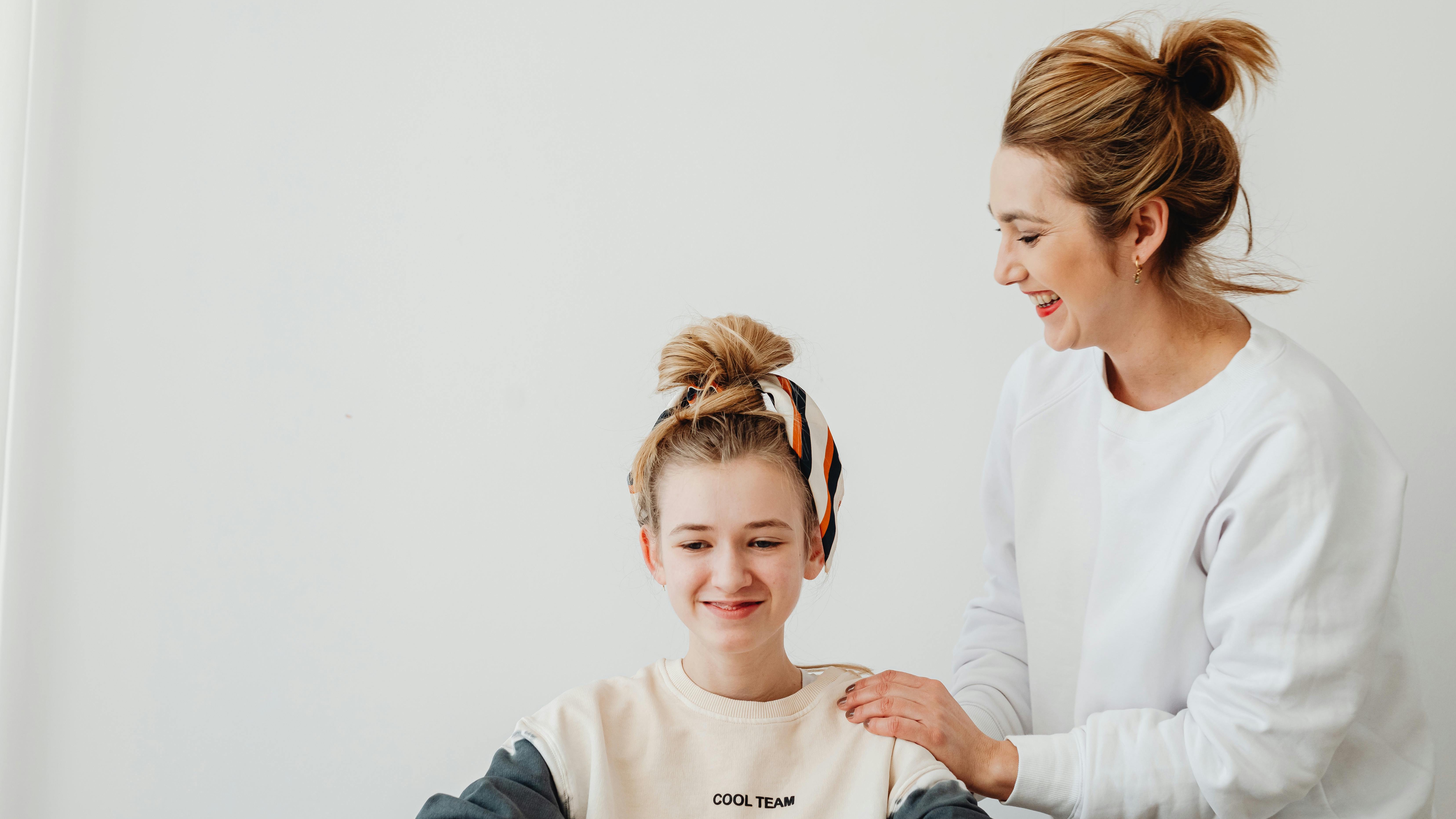 Teen and adult sharing an affectionate embrace in park.