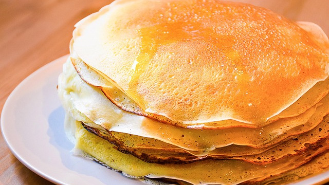 Golden pumpkin protein pancakes with butter and bananas on a plate.