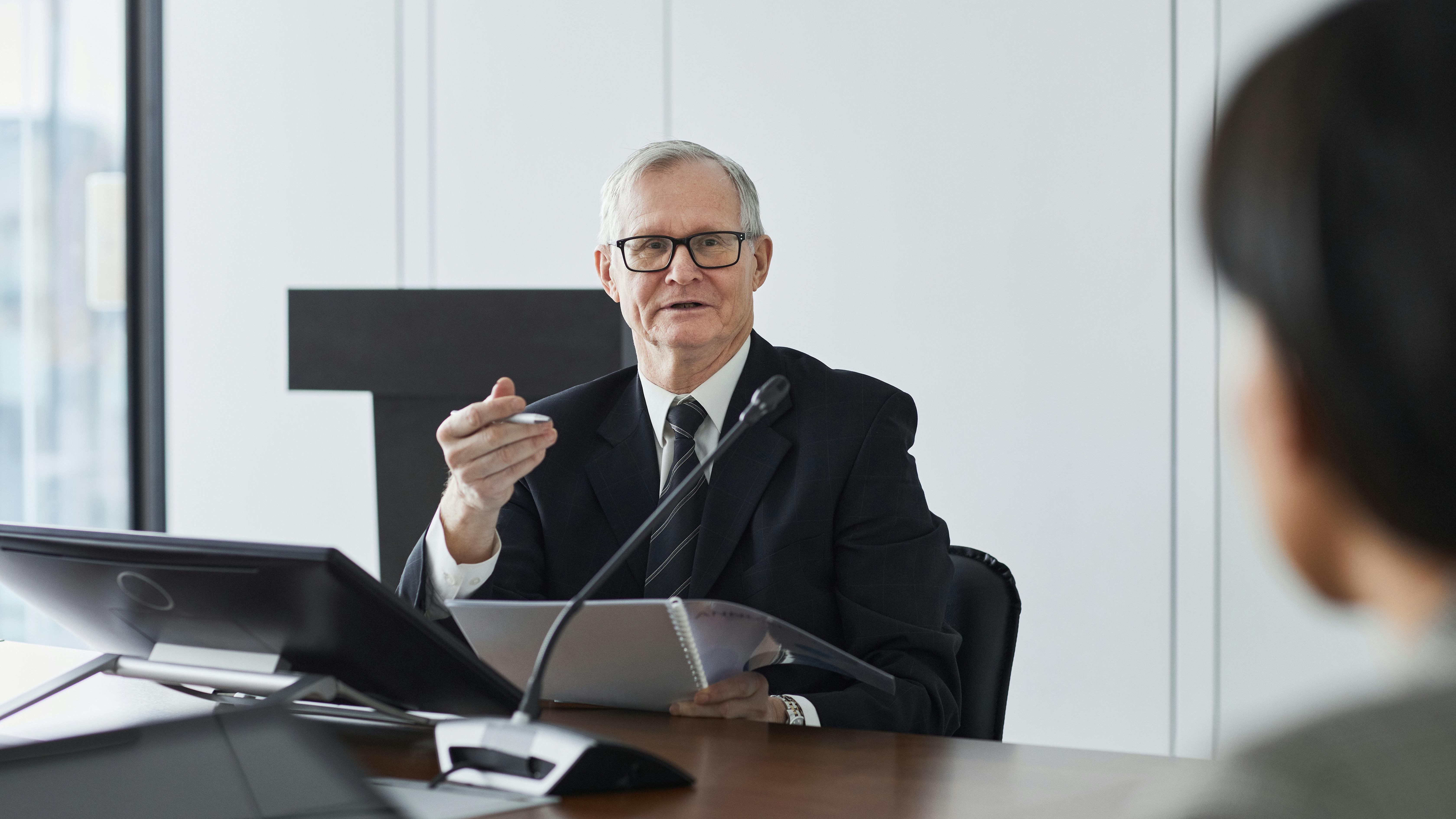Older man using tablet on sofa in bright living room.