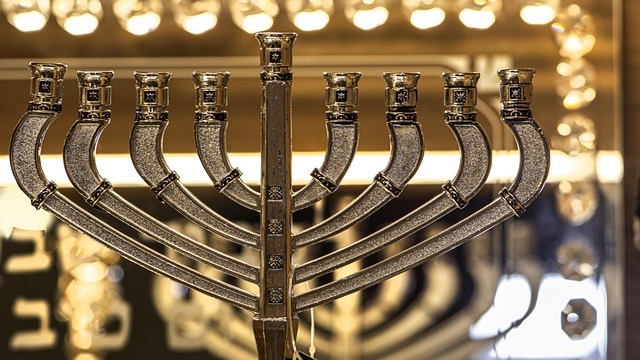 Unique DIY menorah made of potatoes with lit candles.