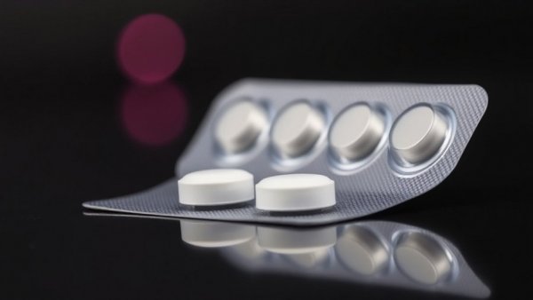 Morning-after pill pack on dark background with soft pink light.