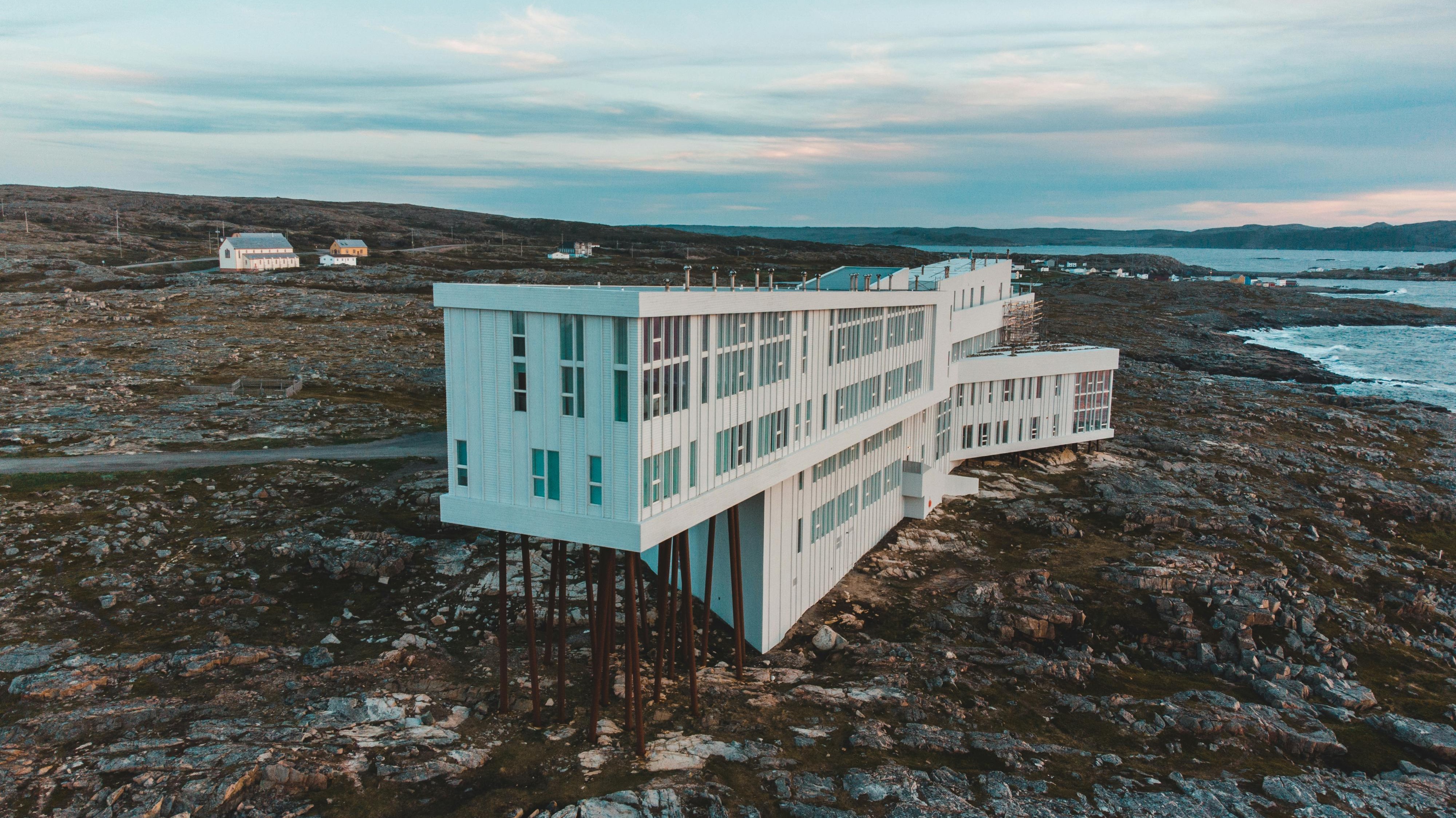 Modern luxury hotel on rugged coastline with crashing waves.