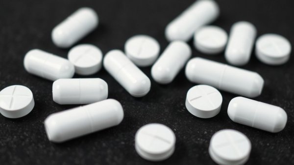 Counterfeit opioids, white pills scattered on black surface.