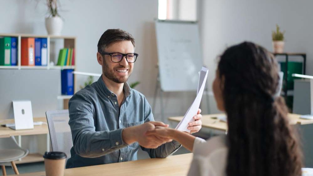 Formal meeting scene discussing candidate screening questions.