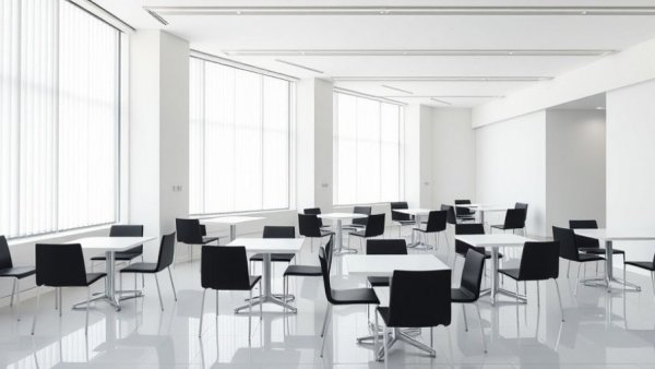 Modern corporate break room with white tables and black chairs.