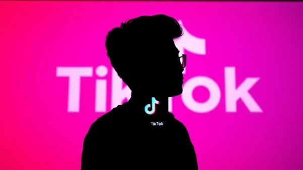 Silhouette holding phone with TikTok logo, vibrant background.