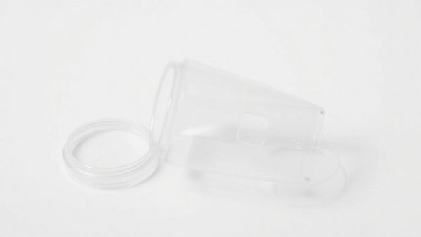 Transparent breast implant removal device with lid on white background.