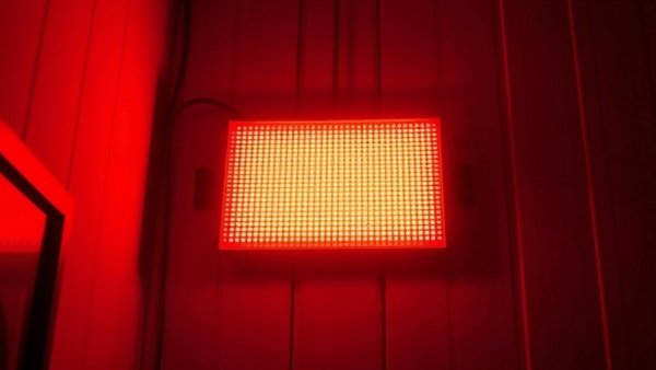Red light therapy panel emitting warm glow in dim setting