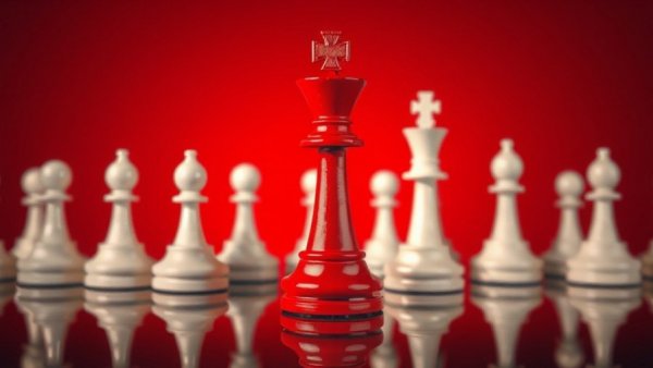 Red chess king among white pawns symbolizing leadership.