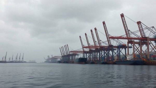 Impact of tariffs on small businesses depicted with harbor cranes.