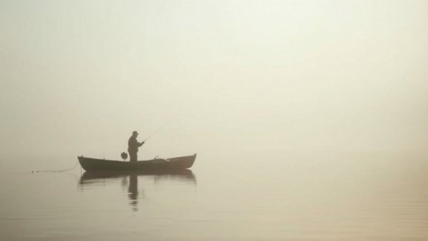 Fisherman casting line on misty Lake Fork during tournament.