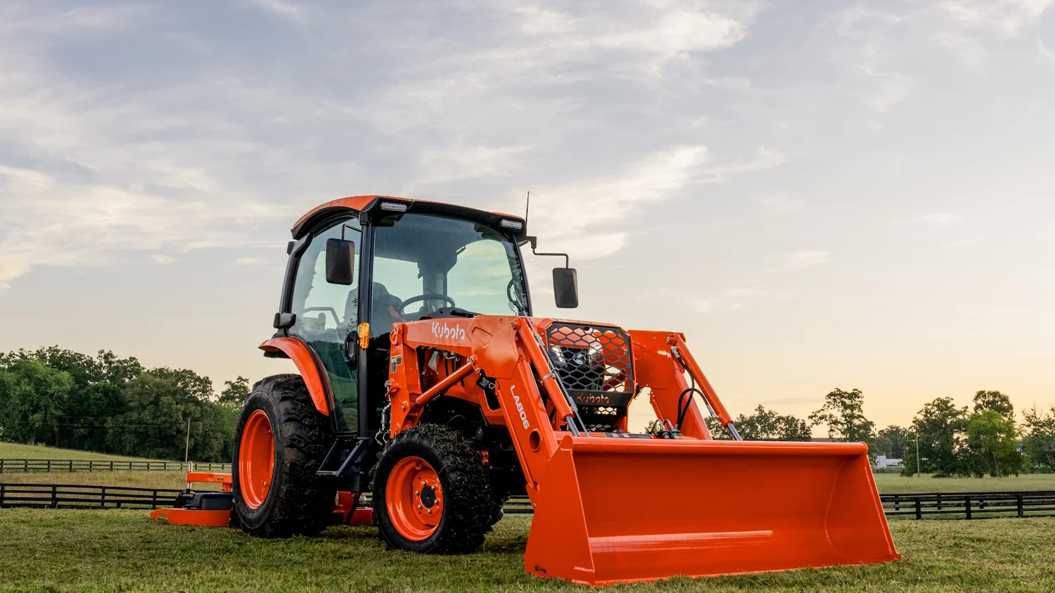 Kubota Grand L70 Compact Tractor in a scenic field at sunset.