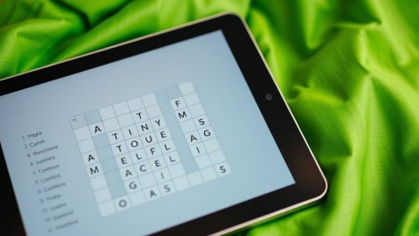 Close-up of NYT Mini Crossword Answers on a tablet, vibrant green background.