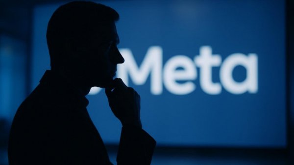 Man silhouetted against large Meta logo, contemplative look