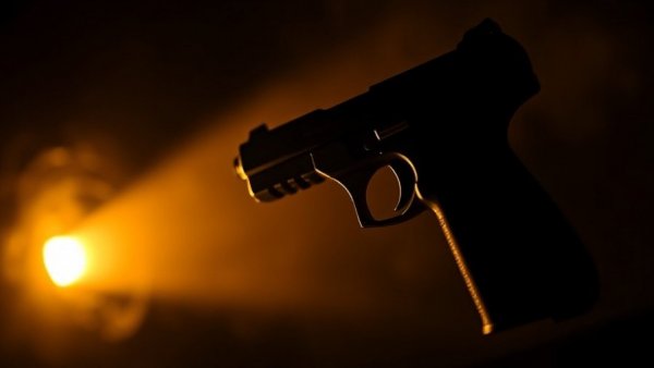Silhouette of a handgun in moody light.