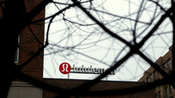 Lululemon logo viewed through tree branches, overcast urban setting.