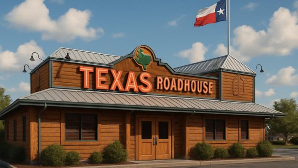 Texas Roadhouse facade with flag and neon sign under clear sky.