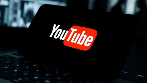 YouTube logo on phone screen above keyboard; AI video labeling concept.