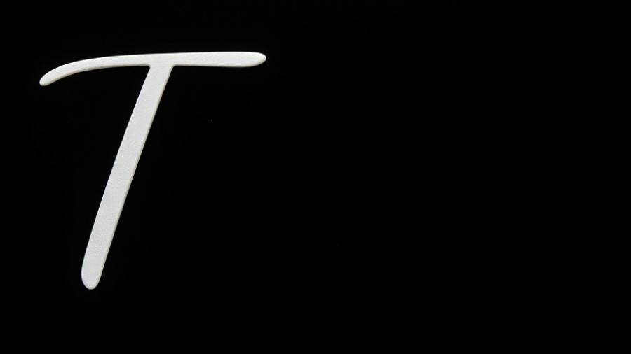 Elegant cursive letter T on a black background, minimalist style.