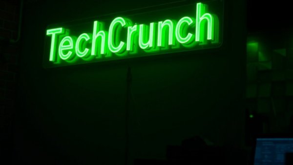 Glowing green neon TechCrunch sign in dark setting
