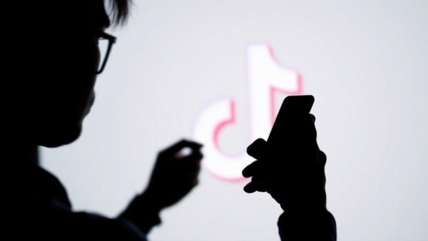 Silhouette with smartphone and TikTok logo, TikTok Oracle outage context.