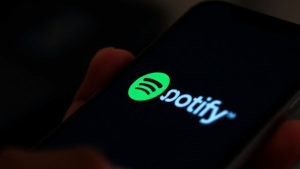 Smartphone showing Spotify logo in dark setting, close-up.
