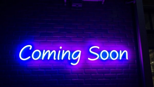 Neon 'Coming Soon' sign glowing against dark brick wall.