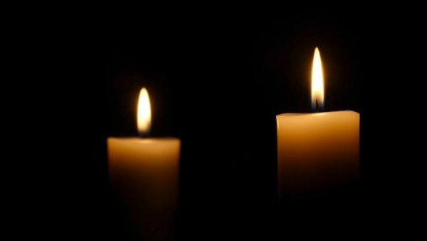 Two glowing candles in darkness for Carrie Anne Fleming obituary.