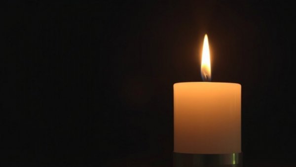 Two burning candles casting a warm glow in darkness.