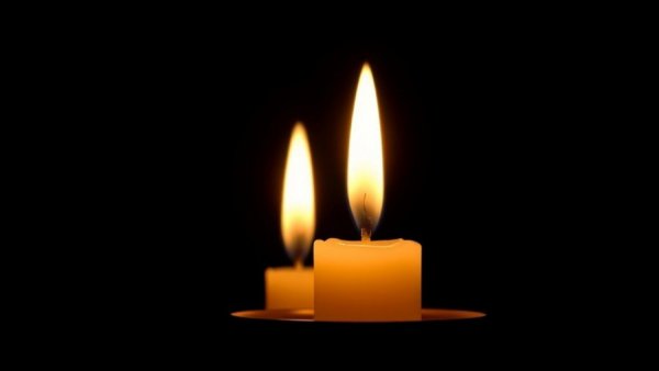 Two glowing candles in darkness, peaceful ambiance.