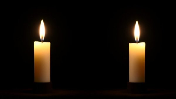 Two softly glowing candles in darkness, Alan Dysert dies commemoration.