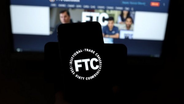 FTC logo on smartphone in dark room, highlighting digital focus related to FTC auto dealer advertising practices.