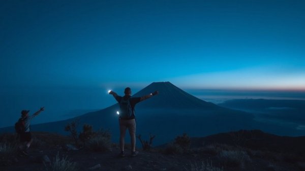 Hikers near Popocatépetl volcano at night, illuminated scene.