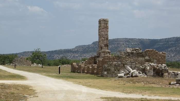 Smiling man in blue shirt at Fort Lancaster Texas historical ruins.