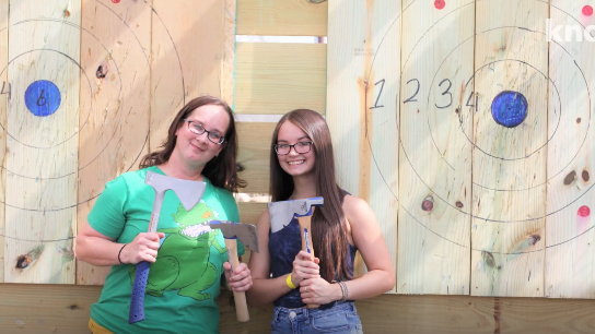Diverse group at axe throwing range, showcasing vibrant Master Skills excitement.