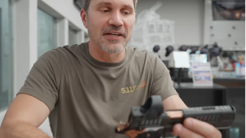 Person examining the Jacob Gray Knox 9 firearm, embodying curiosity with soft lighting.