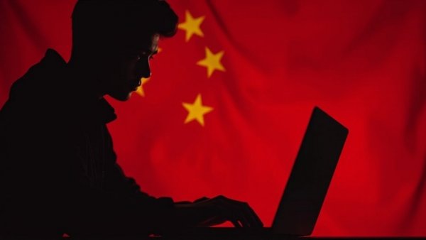 Silhouette of hacker on laptop with Chinese flag background, cybersecurity.
