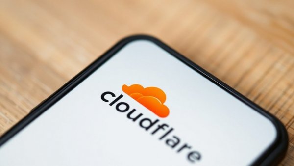 Close-up smartphone with Cloudflare logo, blurred background.