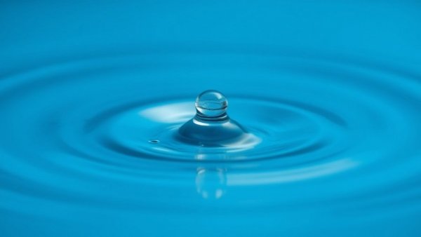 Water droplet impacts calm water surface, creating ripples, symbolizing Dallas Water Utilities service alert cancellation.